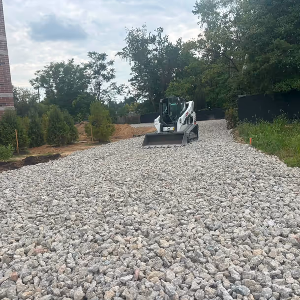 Skid steer spreading fresh crushed stone for a new gravel drive
